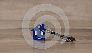 House symbol with silver keys on wood. Real estate concept