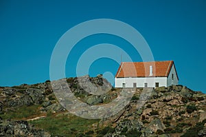 House on top of hilly landscape with bushes and rocks