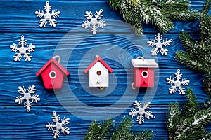 House toys and snowflakes for new year celebration with fur tree branches on blue wooden background top veiw