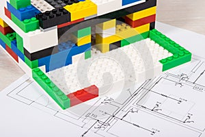 House under construction made of toy blocks and electrical installation plan. Building or renovating home
