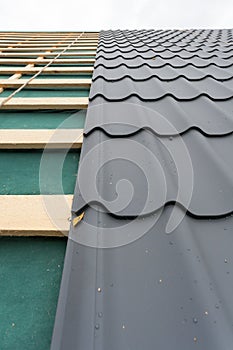 House under construction.Roof with metal tile,screwdriver and roofing iron.