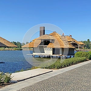 House on the water in summer day, beach landscape with river, sky and house
