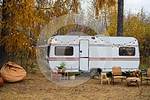 House on wheels. Cozy wicker furniture by the van against the backdrop of an autumn forest.