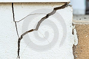 A house white wall with a large crack. Grunge concrete cement white wall with a crack in an industrial building