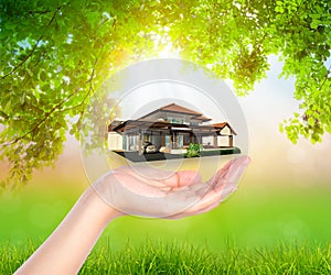 House on woman hand over Green leaf