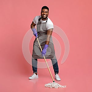 Household Chores. Happy African Janitor Washing Floor With Mop And Smiling