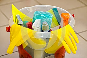 Household cleaning tools and products in a plastic bucket