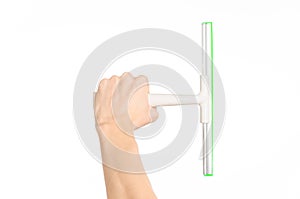 Household cleaning and washing windows theme: man's hand holding a green scraper windows isolated on a white background in the stu