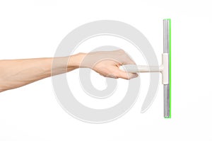 Household cleaning and washing windows theme: man's hand holding a green scraper windows isolated on a white background in the stu