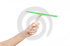 Household cleaning and washing windows theme: man's hand holding a green scraper windows isolated on a white background in the stu