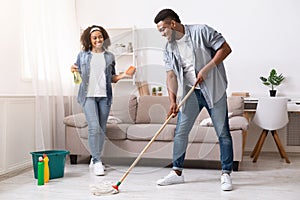 Household Concept. Happy Black Couple Enjoying Cleaning House Together