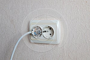 Household electrical outlet with a broken electrical plug inside. Bare live wires sticking out of the Electric socket
