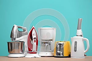 Different household and kitchen appliances on table against color background. Interior element