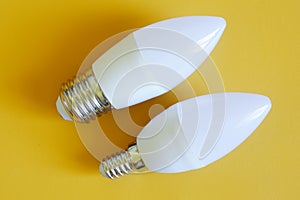 Household LED bulbs on a yellow background. Comparison of small - E14 and large - E27 LED lamp base