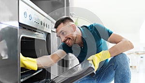 Man with rag cleaning inside oven at home kitchen