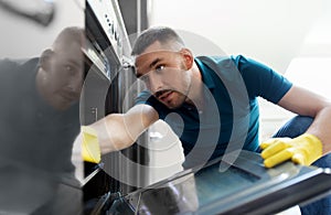 Man with rag cleaning inside oven at home kitchen