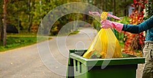 Household waste - hand insert yellow plastic unsorted garbage bag into trash bin on the street. copy space