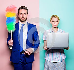 Househusband and female boss. Businessman and housewife. Family couple. Husband stand with dust brush while wife holding