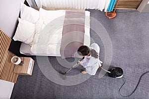 Housekeeper Cleaning Carpet With Vacuum Cleaner