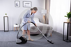 Housekeeper Cleaning Carpet With Vacuum Cleaner