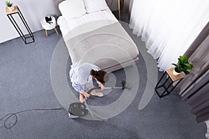 Housekeeper Cleaning Carpet With Vacuum Cleaner