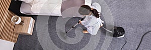 Housekeeper Cleaning Carpet With Vacuum Cleaner