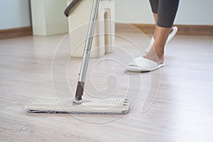 Housekeeper cleaning floor of living room by mob