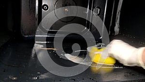 Housekeeper cleaning oven with household chemicals