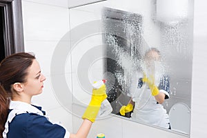 Housekeeper cleaning a wall mirror