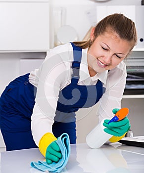 Housekeeper female 20-25 years old is cleaning dust from the desk