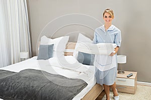 Housekeeper holding stack of sheet