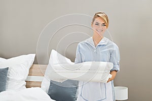 Housekeeper holding stack of sheet
