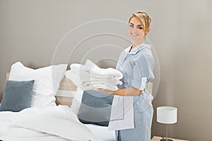 Housekeeper Holding Stack Of Sheet