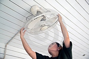 The maidservant is installing and cleaning the ceiling fan.