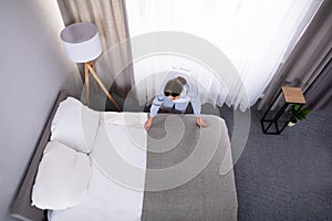 Housekeeper Making Bed In Hotel Room