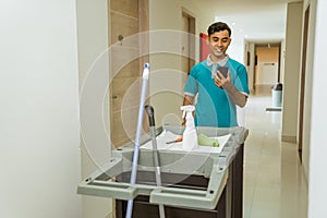 housekeepers using cellphones while pushing carts filled with tools