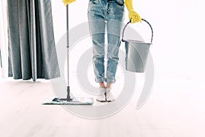 Housekeeping and cleaning concept. Happy young woman in blue rubber gloves wiping dust using mop while cleaning on floor at home