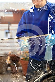 Housekeeping: cleaning the windows, Window cleaner using a squeegee, sponge and soap suds to wash a window