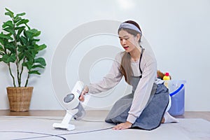 Housekeeping concept, Housemaid hold vacuum cleaner to vacuuming and cleaning carpet on the floor