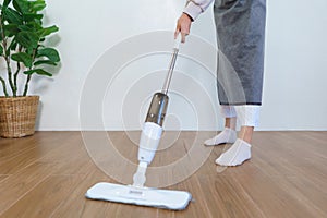 Housekeeping concept, Housemaid use mop to mopping and cleaning dust on the floor in living room