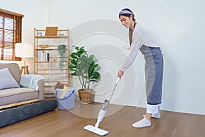 Housekeeping concept, Housemaid use mop to mopping and cleaning dust on the floor in living room