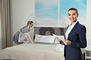 Housekeeping manager with tablet checking maid work in hotel room