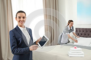 Housekeeping manager with tablet checking maid work in hotel room