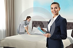 Housekeeping manager with tablet checking maid work in hotel room