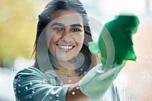 Housekeeping, portrait and cleaner cleaning the window with a cloth by her home or apartment. Female maid, housekeeper