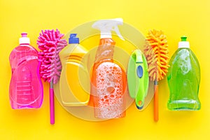 Housekeeping set. Detergents, soap, cleaners and brush for housecleaning on yellow background top view mock-up