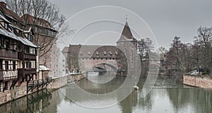 Houses and a bridge reflected in a river in the old town of Nuremberg seen from Henkersteg covered bridge across Pegnitz river