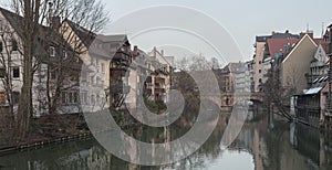 Houses and a bridge reflected in a river in the old town of Nuremberg seen from Henkersteg covered bridge across Pegnitz river