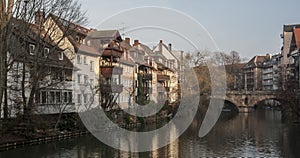 Houses and a bridge reflected in a river in the old town of Nuremberg seen from Henkersteg covered bridge across Pegnitz river