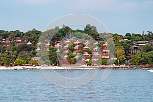 Houses built on a hill in Phi Phi Island. Longtail boats and andaman sea in the foreground